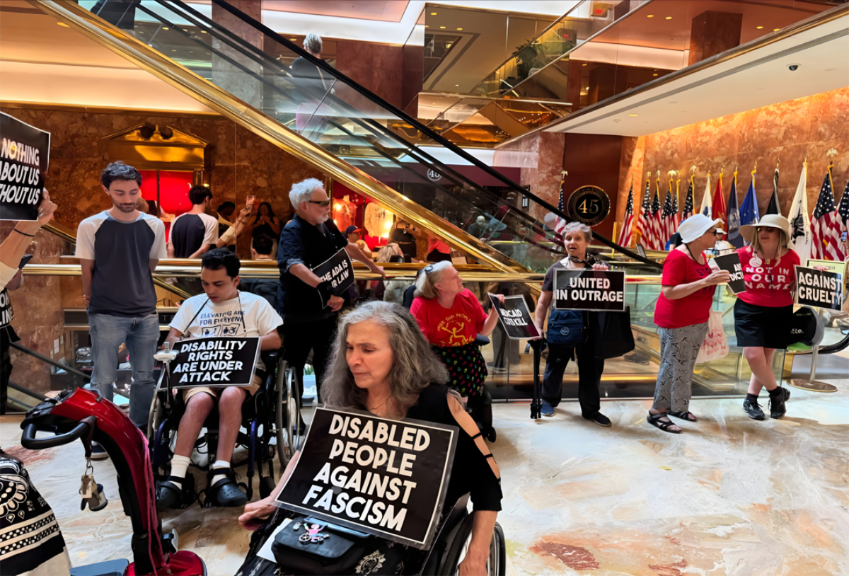 Disability rights protesters holding signs inside a building lobby near escalators.