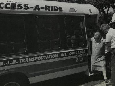 A paratransit driver helps a woman off the vehicle