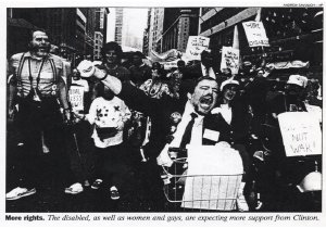 A black and white news photo of a passionate crowd of disability rights protesters shouting and raising their fists.