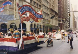 Parade float decorated with patriotic banners moving past spectators and police on a city street.