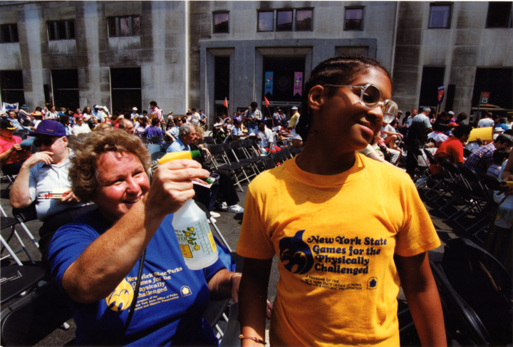 A woman sprays water on a young boy to help him cool off in the hot summer weather.