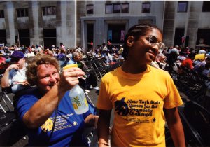 A woman sprays water on a young boy to help him cool off in the hot summer weather.
