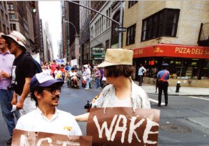Two disability rights marchers hold large, handwritten cardboard signs on a city street