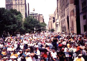 Protesters and wheelchair users gather on a wide city street during a demonstration.