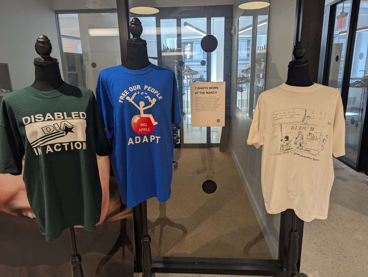 Three t-shirts in a gallery space on mannequins