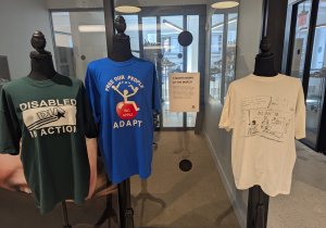 Three t-shirts in a gallery space on mannequins