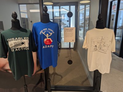 Three t-shirts in a gallery space on mannequins