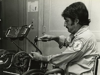 A veteran in a wheelchair fixes a manual wheelchair